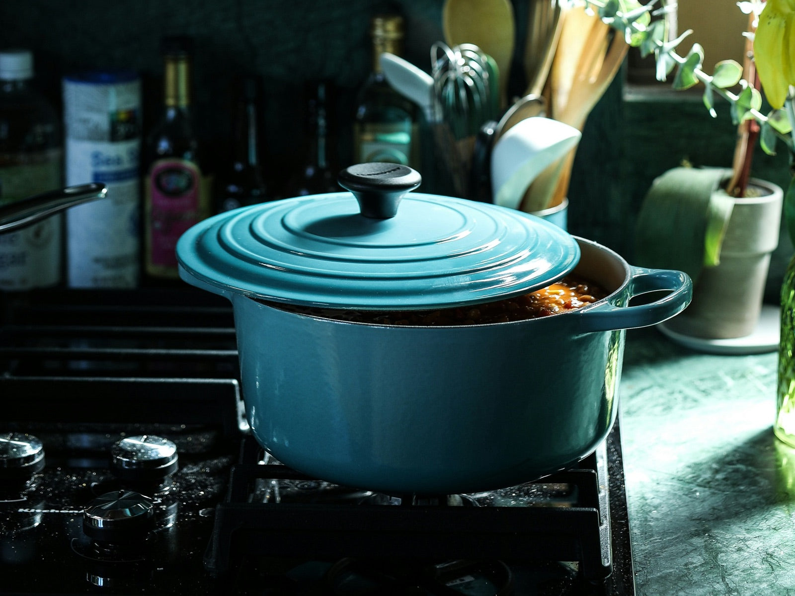 Teal enameled cast iron Dutch oven with lid on a gas stovetop