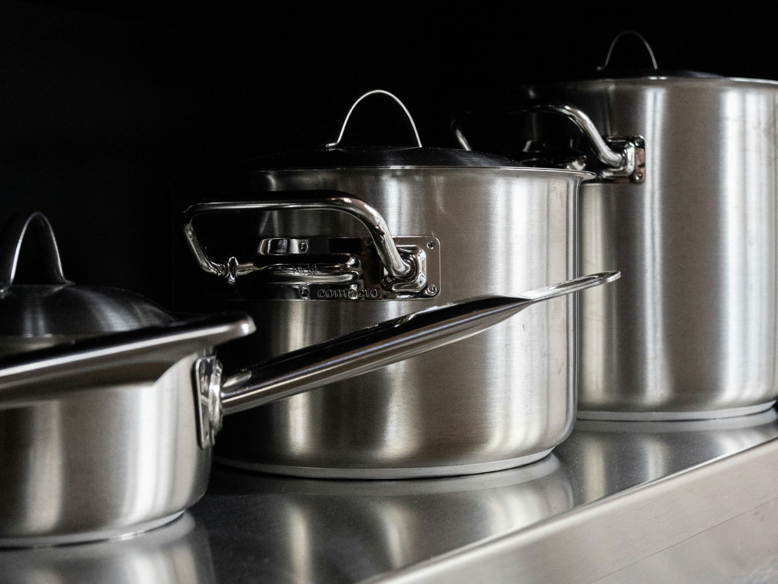 Close-up of stainless steel pots with sturdy riveted handles, showing durable cookware construction